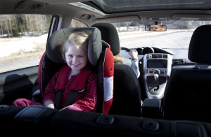 Jente i 3-4 årsalder sitter i bakovervendt bilstol.
